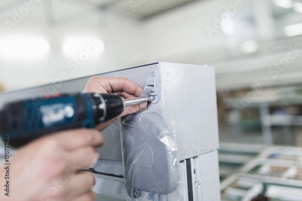 Fototapeta Manual worker assembling PVC doors and windows. Manufacturing jobs. Selective focus. Factory for aluminum and PVC windows and doors production.