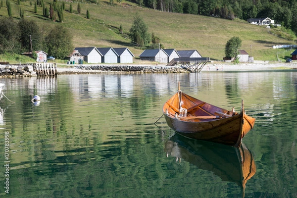 Fototapeta Wooden rowing boat  and boathouses in the background