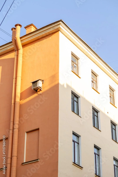 Fototapeta Air conditioners on the facade of a yellow house against a blue sky. An air ventilation and cooling system and air purification technologies are installed. split system.
