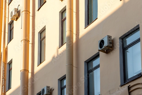 Fototapeta Air conditioners on the facade of yellow historical house. An air ventilation and cooling system and air purification technologies are installed. split system. cooling in hot weather. climate.