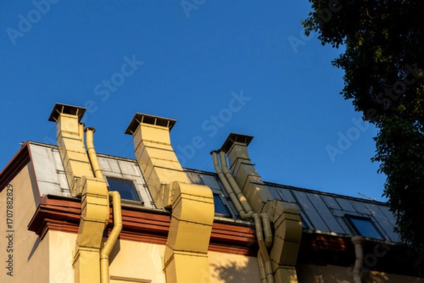 Fototapeta building with three chimneys on the roof. chimneys are yellow and the roof is brown. the historical area of the city. restoration and preservation of the city's appearance.