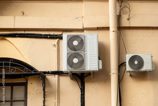Fototapeta Air conditioners on the facade of yellow historical house. An air ventilation and cooling system and air purification technologies are installed. split system. cooling in hot weather. climate.