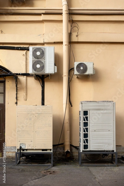 Fototapeta Air conditioners on the facade of yellow historical house. An air ventilation and cooling system and air purification technologies are installed. split system. cooling in hot weather. climate.