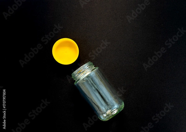 Fototapeta Empty Glass Jar with Yellow Lid on Black Background