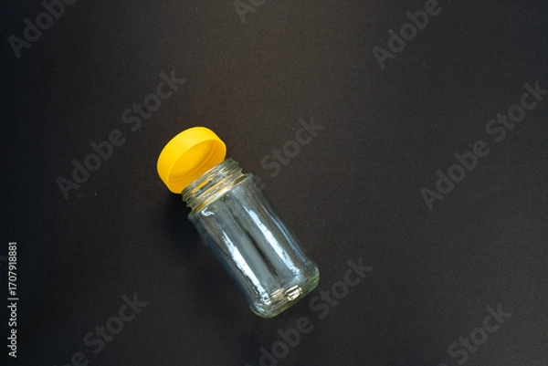 Fototapeta Transparent Glass Jar with Yellow Lid on Black Background with Copy Space