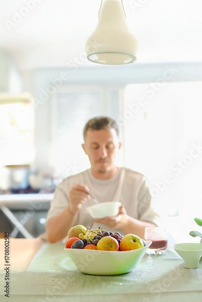 Fototapeta Man Chewing a Bite of Oats While Sitting an his Dinning Table.