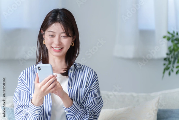 Obraz スマホを使う笑顔の若い女性