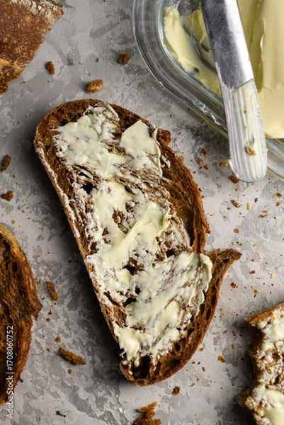 Fototapeta Top view of sliced rye sourdough bread with butter and knife close up. Food background
