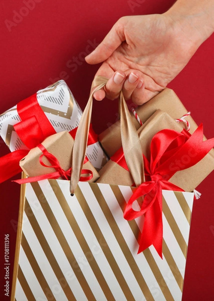 Obraz Paper bag full of christmas gifts close up with place to place text. Vertical photo format