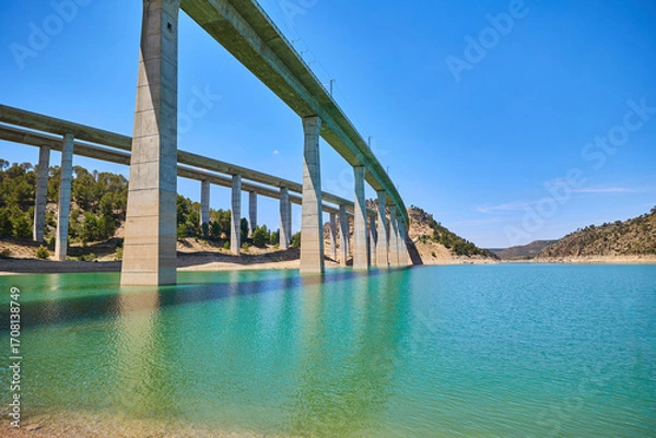 Fototapeta Tranquil scenery under a bridge over a reservoir with crystal clear turquoise water