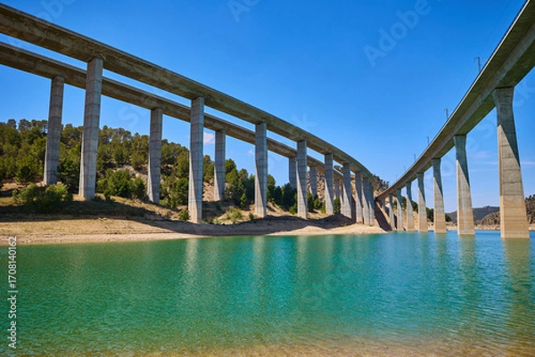 Fototapeta Tranquil scenery under a bridge over a reservoir with crystal clear water