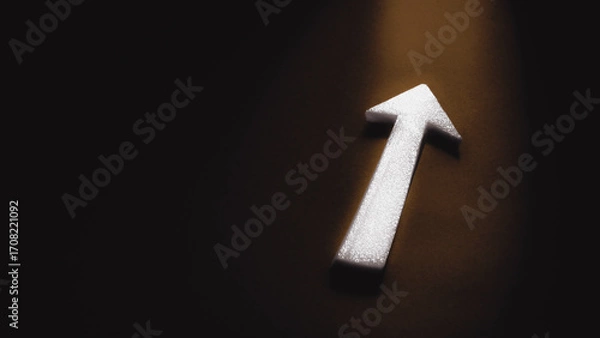 Fototapeta A white arrow points exit towards the light on a dark background with copy space, symbolizing business direction, progress, success and strategy.