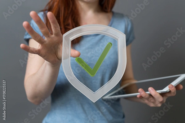 Fototapeta Stock photo of a woman presenting a digital shield with a check mark, symbolizing online security, data protection, and safety.