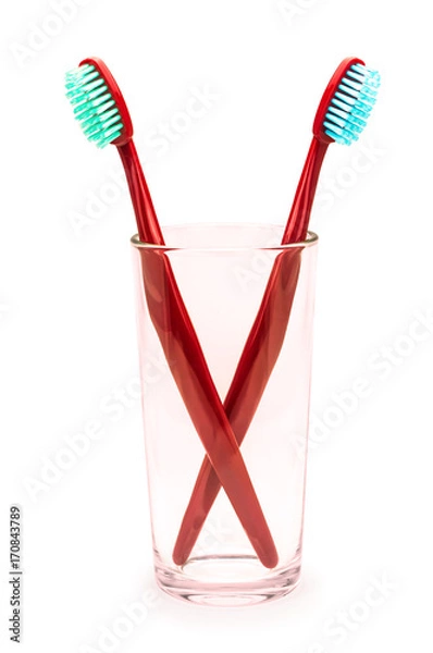 Obraz Две красные зубные щетки в стекляном стакане на изолированном белом фоне