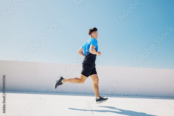Fototapeta Man running on rooftop during workout session in the city