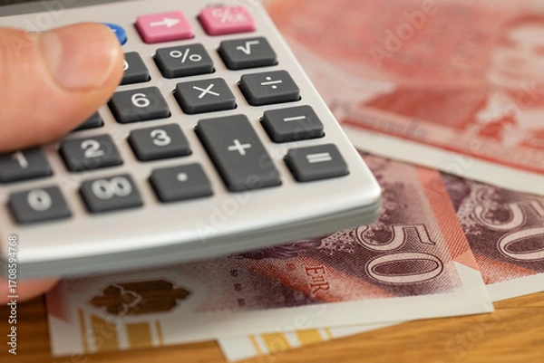 Fototapeta UK money. 50 British pound notes and a pocket calculator held in a hand. Financial concept, currency exchange, market rate, household budget, expense analysis