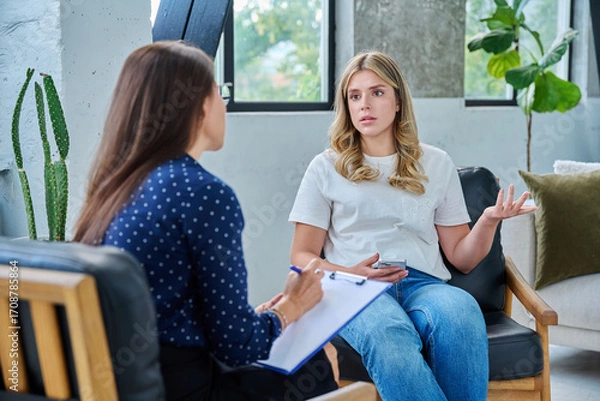 Fototapeta Young woman patient talking with female psychologist, mental counselor