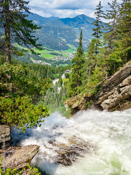Fototapeta Krimml, Austria - 08-06-2025 : Waterfall flowing down shot from above at the  Krimml Waterfalls, mountains in background.