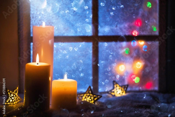 Fototapeta Winter decoration with candles near the snow-covered window