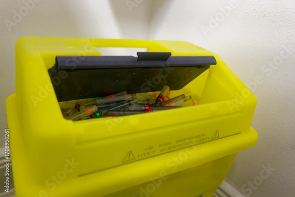 Fototapeta Yellow medical sharps container with lid and visible needles