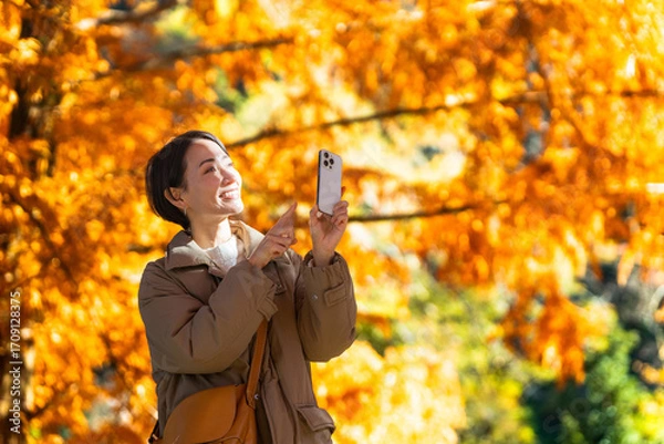 Obraz 紅葉をスマートフォンで撮影している女性　ライフスタイルイメージ