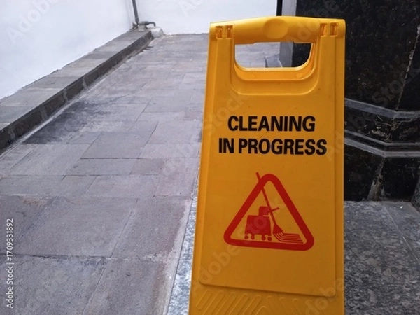 Fototapeta A yellow board is used to inform that the area is in the process of being cleaned