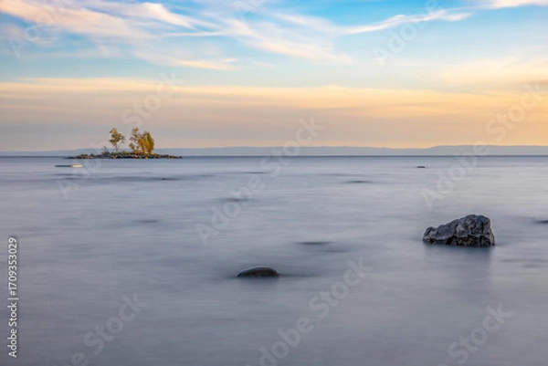Obraz A stunning sunset over a serene beach in Tiny, Ontario, capturing the tranquil beauty and vibrant colors of the evening sky reflecting on the calm waters.