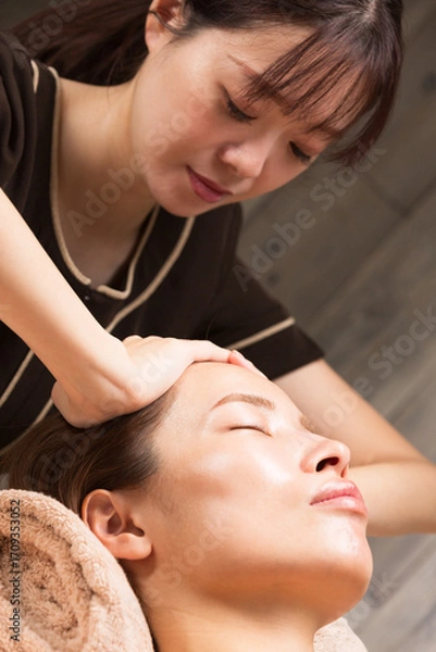 Fototapeta 若いアジア人のエステティシャンはヘッドマッサージしている。