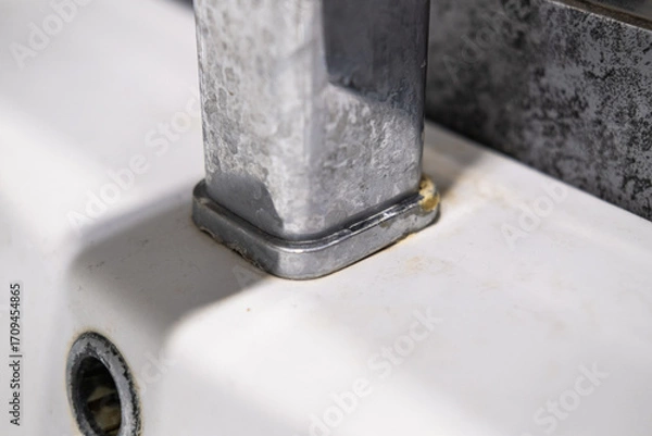Fototapeta A dirty metal faucet in the sink with limescale, rust marks, and grime around the mixer, showing neglect and the need for cleaning.