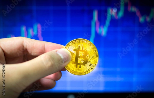 Obraz Man holding gold bitcoin and BTC trading chart in background, Financial concept