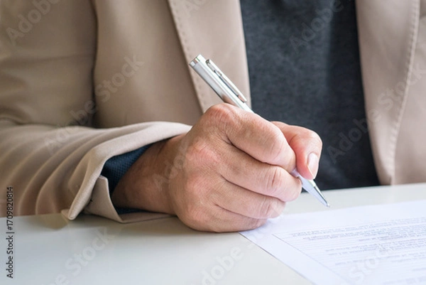Fototapeta Businessman looking at document about to write or sign on it.