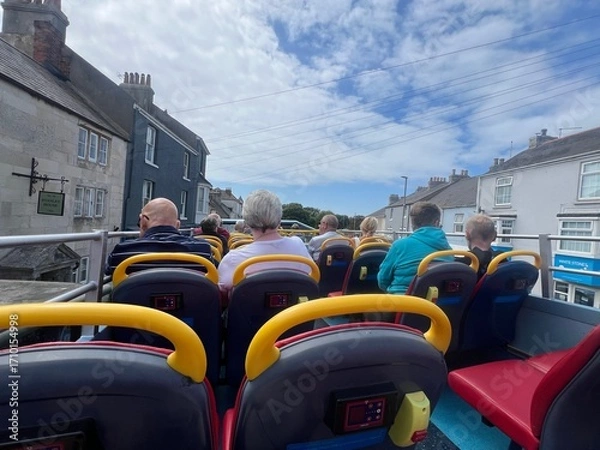Fototapeta Passengers on the top open floor of an open top bus on a summer trip in Portland Dorset UK