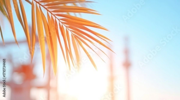 Fototapeta Golden Leaf in Sunshine: Close-up of a golden leaf in bright sunlight, with hints of other greenery framing the scene and a clear, crisp blue sky in the backdrop.