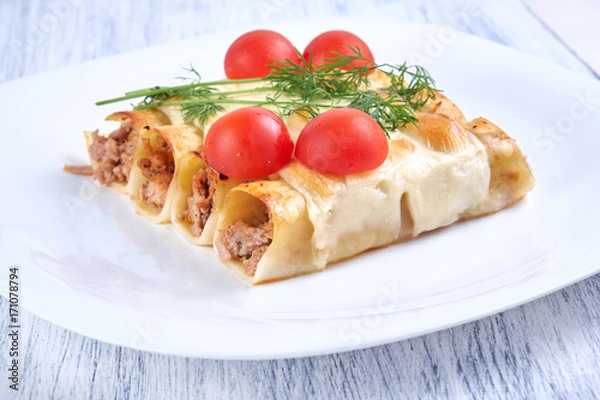 Fototapeta Baked cannelloni with cheese and tomatoes on a white plate