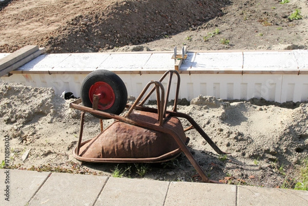 Fototapeta a wheelbarrow lies upside down at a construction site in the countryside 