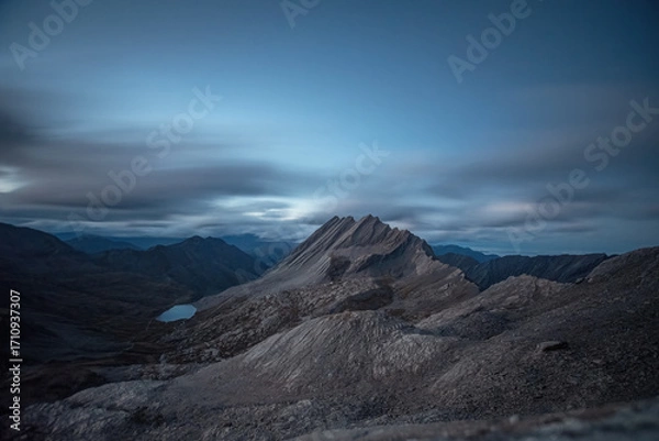 Fototapeta Crête de la Taillante (Taillante crest) stands out against the dramatic sky of a summer evening, with the Foréant lake illuminated by the last light at its foot. Cottian Alps. 