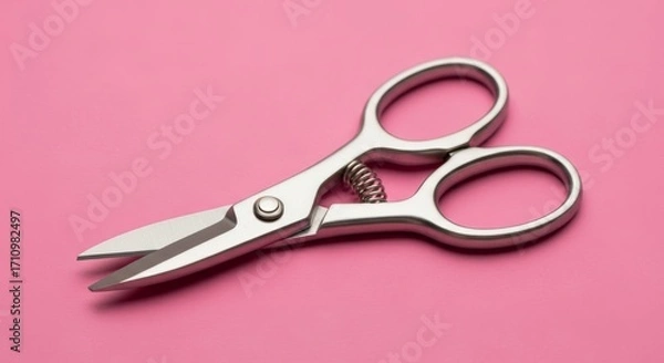 Fototapeta Metal scissors lying on a pink surface close up