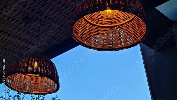 Fototapeta Lampshades are woven from wicker and hung on the summer veranda with lights on
