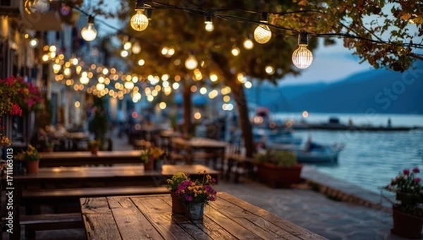 Obraz Charming waterfront restaurant terrace illuminated by warm string lights at dusk.