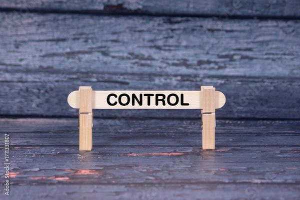 Fototapeta Control symbol. Wooden stick fastened by Clothespins, A lightly orange toned grunge wooden background. Business and Control concept with copy space