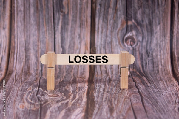 Fototapeta Losses symbol. A wooden stick clasped by clothespins set over a beautiful Brown Grunge Wooden Texture Background. Business and Losses concept with copy space
