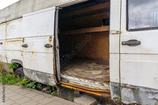 Fototapeta Old abandoned delivery van with open side door, rusty bodywork, and empty interior