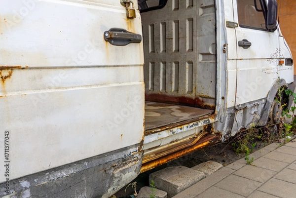 Fototapeta Old abandoned delivery van with open side door, rusty bodywork, and empty interior
