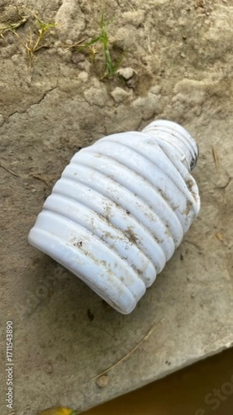 Fototapeta Plastic bottle in a Natural Setting: A weathered, discarded plastic bottle lies on the parched earth. The image evokes contemplation about waste and its pervasive impact.