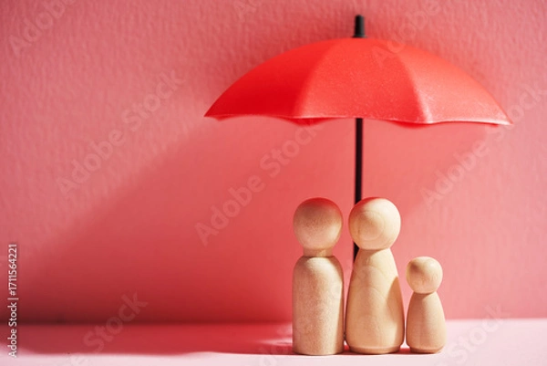 Fototapeta Umbrella and wooden dolls with copy space. Family protection and insurance coverage concept.