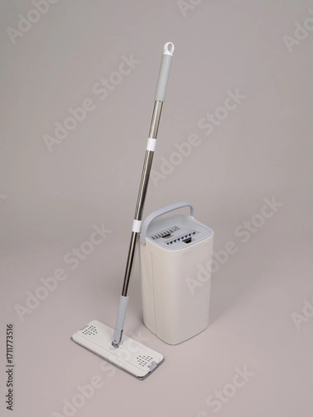 Obraz Modern plastic bucket with a special hole for wringing out a rag and a mop with a metal handle on a gray background