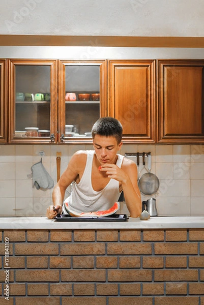 Fototapeta Adolescent Male Enjoying a Nutritious Snack in a Bright Dining Room.