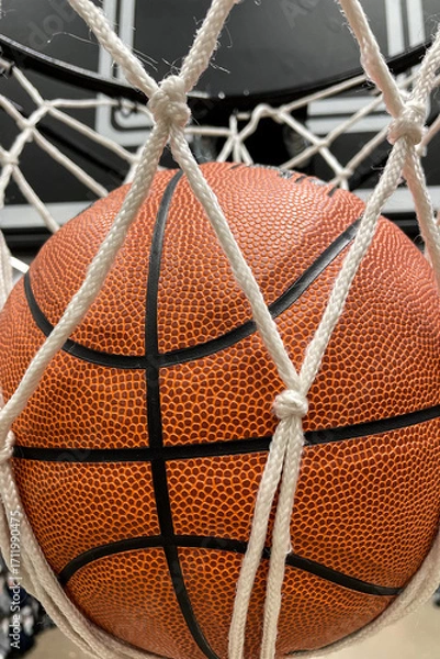 Fototapeta Close-up of an orange basketball falling through a basketball hoop and a white nylon net