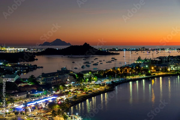 Fototapeta View at night of  the harbor and the bay of Marigot in the Caribbean island of Saint Martin (St Maarten), French West Indies. Saba island in the background