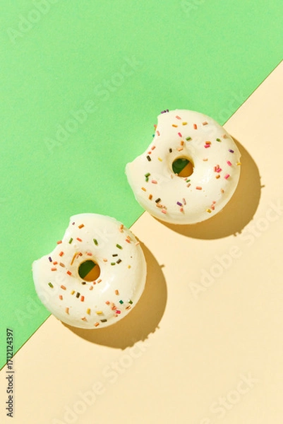 Fototapeta Overhead view of various donuts with confetti arranged on colored background